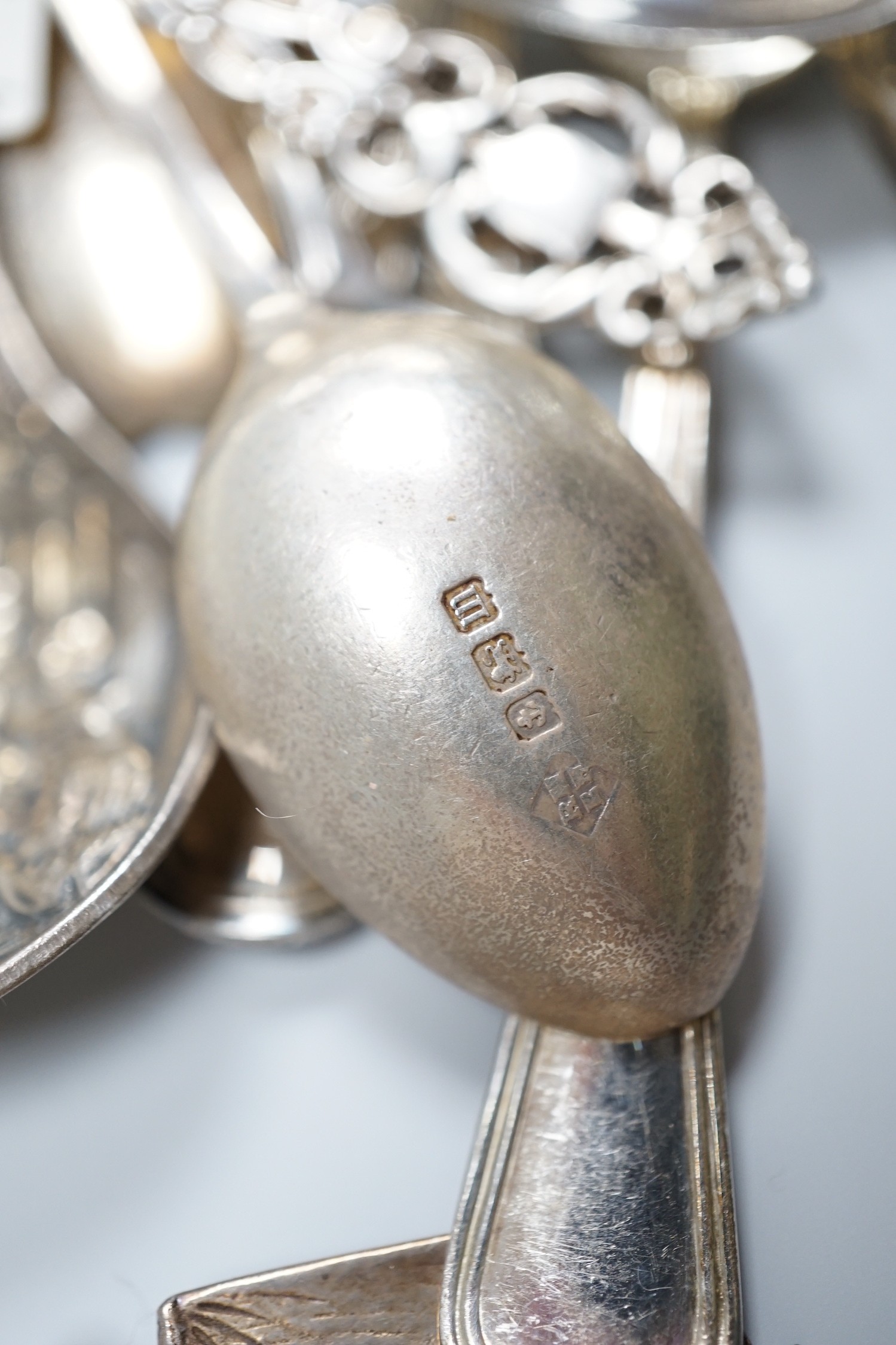 A group of mixed silver and white metal items including flatware, Dutch fish slice, German 800 tea strainer, George IV 'Claret' wine label, etc. and a plated spoon.